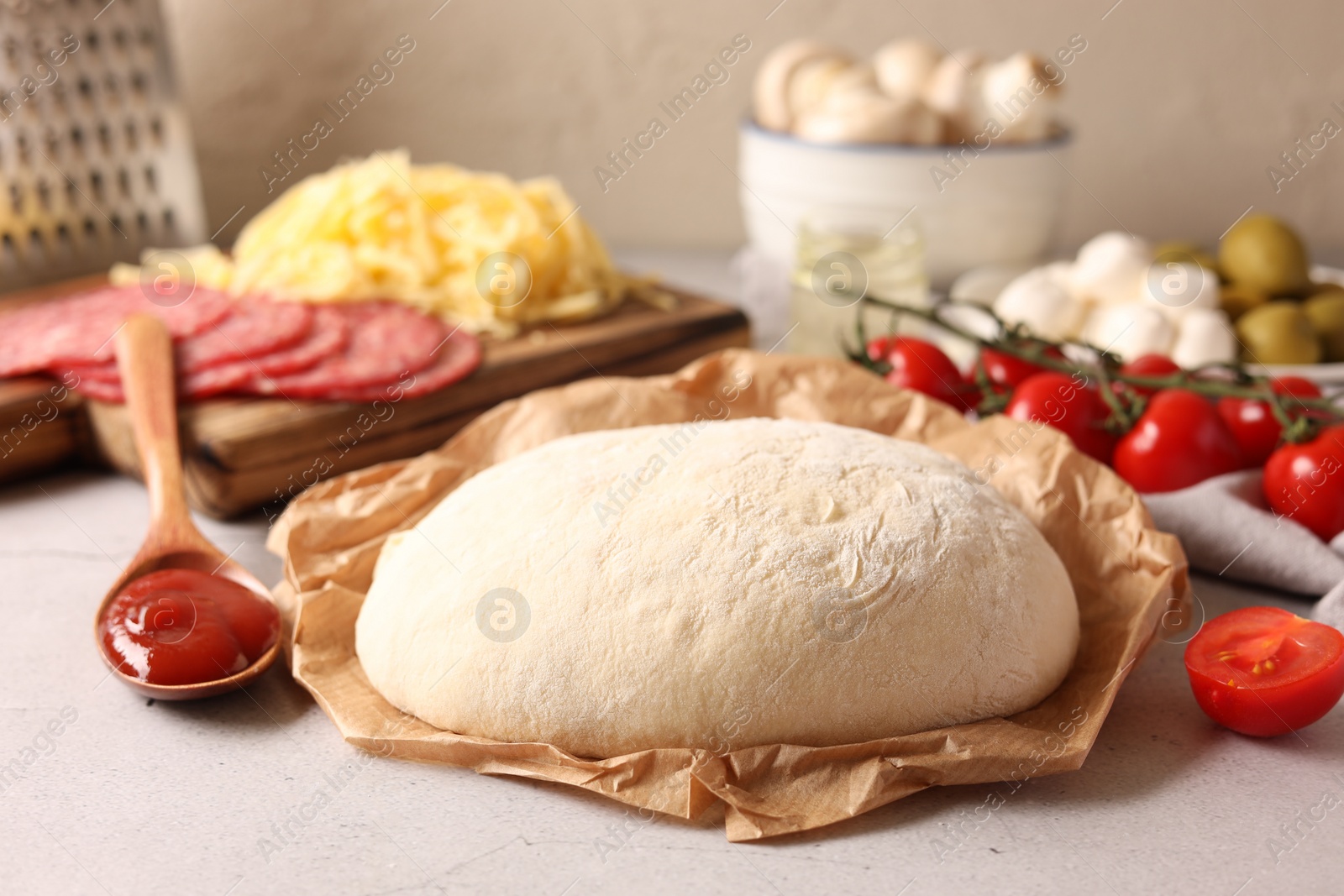 Photo of Pizza dough and products on gray textured table, closeup