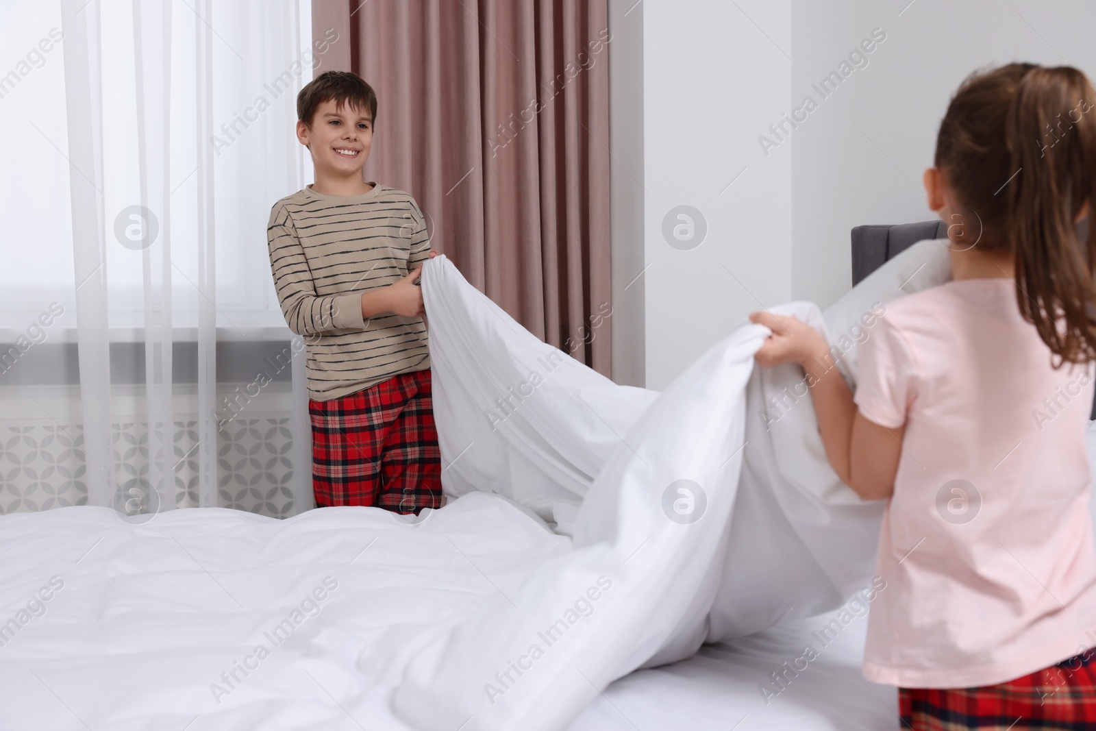 Photo of Brother and sister changing bed linens together in bedroom