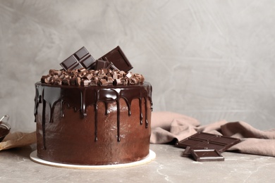 Photo of Freshly made delicious chocolate cake on marble table against grey background. Space for text