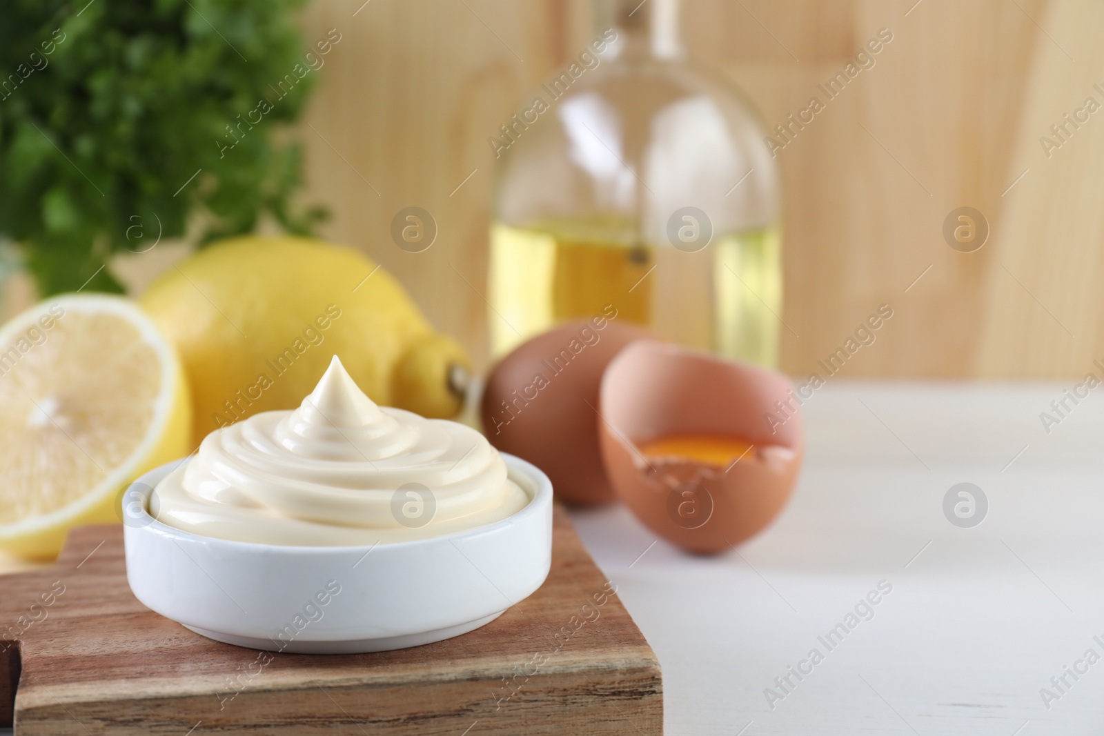 Photo of Fresh mayonnaise sauce in bowl on white wooden table, space for text