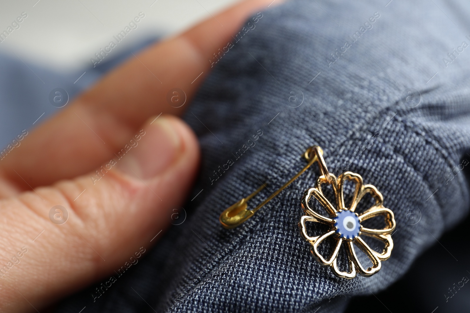 Photo of Woman holding clothing with evil eye safety pin, closeup