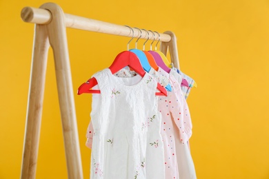 Photo of Rack with stylish children clothes on yellow background