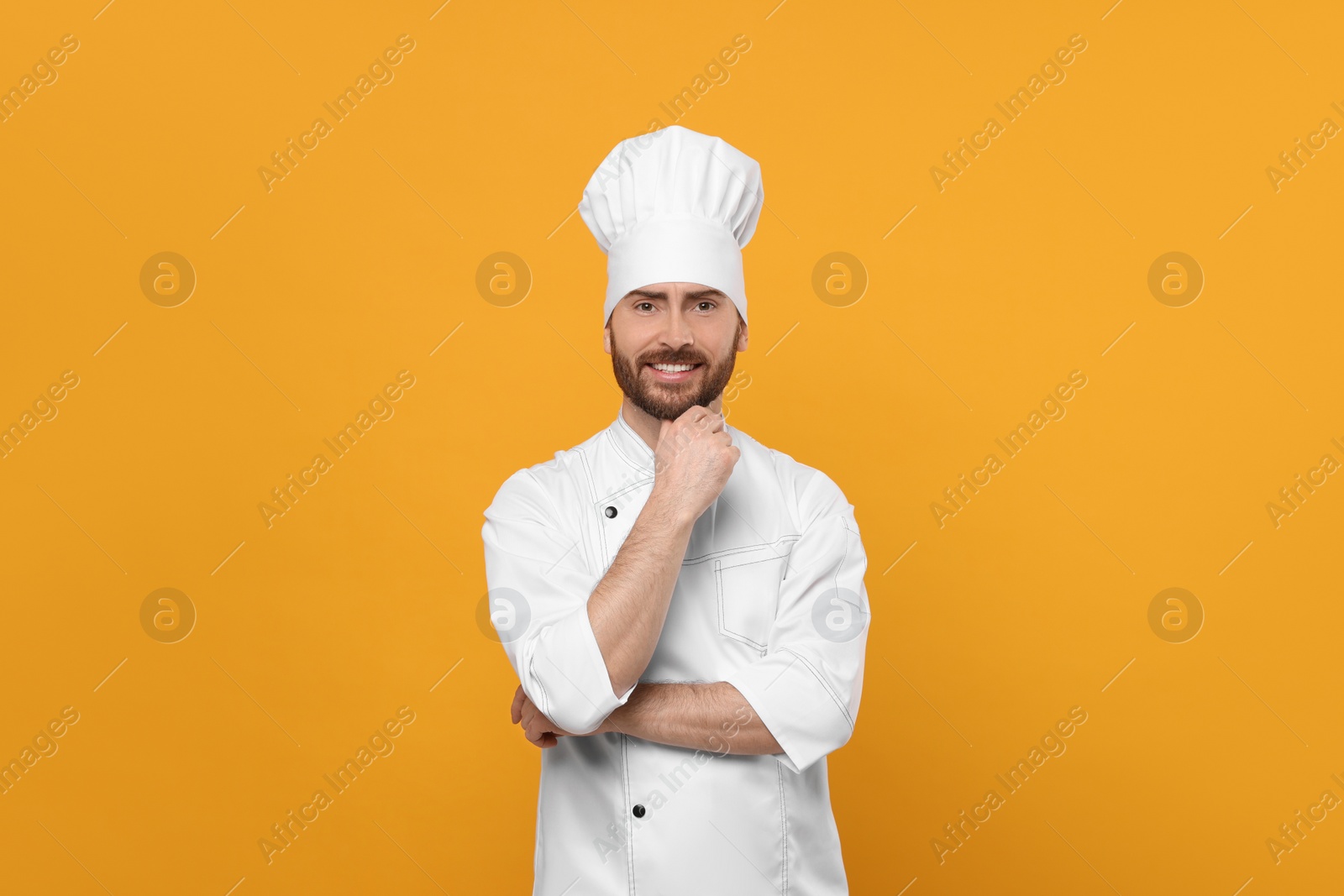 Photo of Smiling mature male chef on orange background