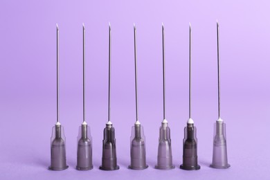 Photo of Many disposable syringe needles on violet background