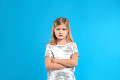 Upset little girl on light blue background