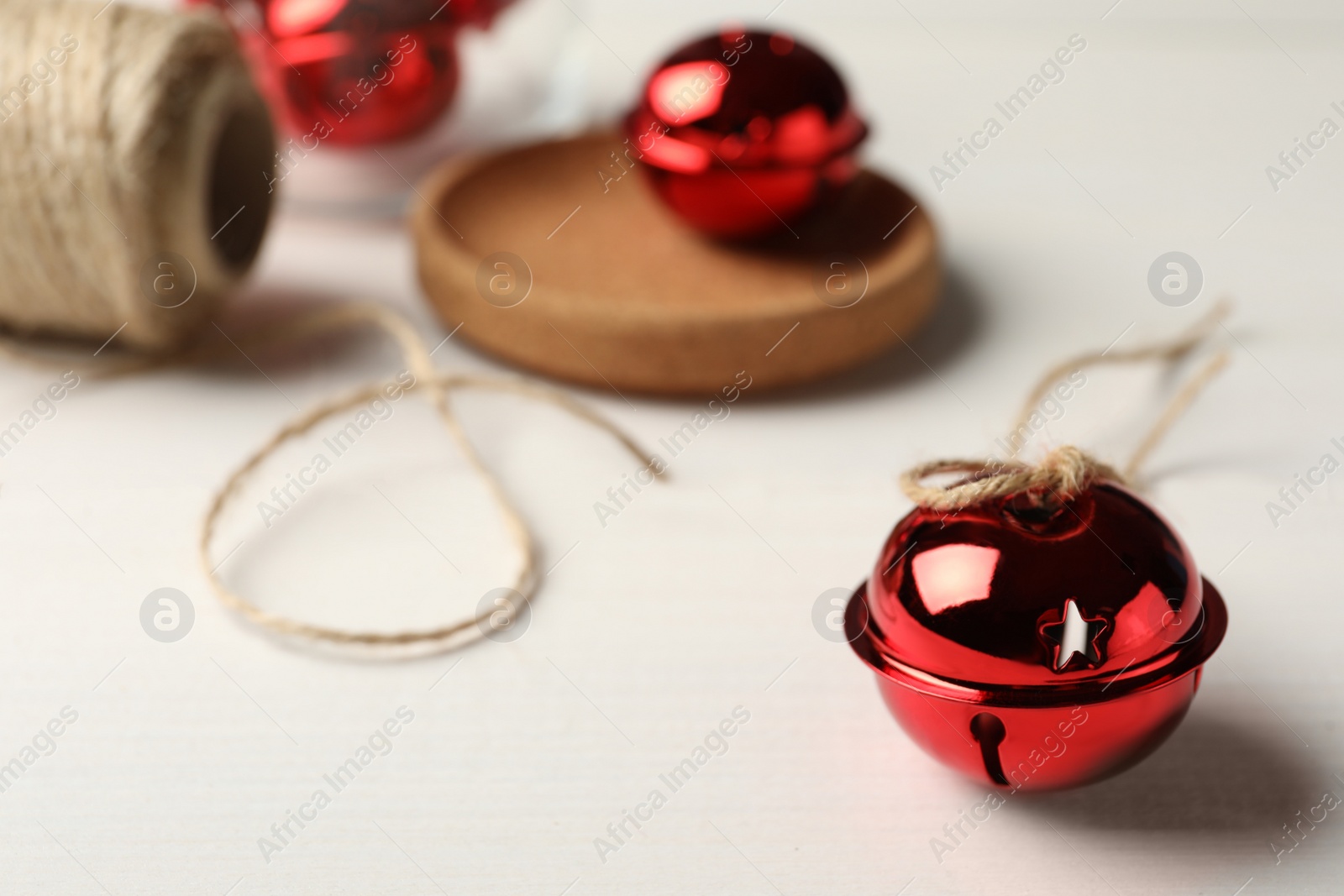 Photo of Red sleigh bell with rope on white table. Space for text