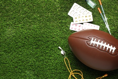 Photo of American football ball, whistle and different drugs on green grass, above view with space for text. Doping concept