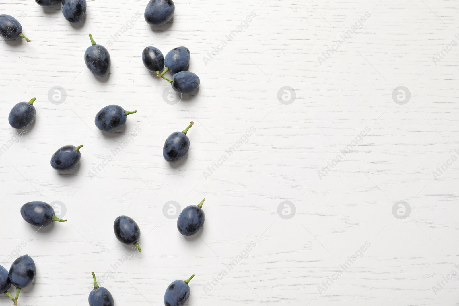 Photo of Fresh ripe juicy grapes on white wooden background, top view. Space for text