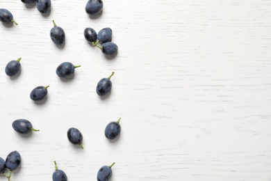 Fresh ripe juicy grapes on white wooden background, top view. Space for text