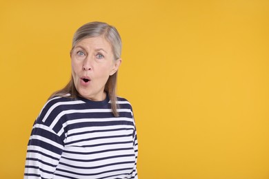 Photo of Portrait of surprised senior woman on yellow background, space for text