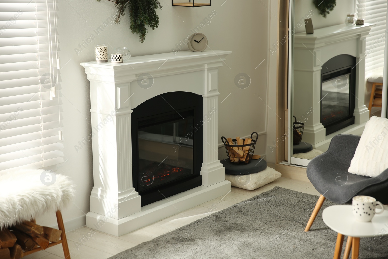 Photo of Bright living room interior with artificial fireplace and firewood in basket