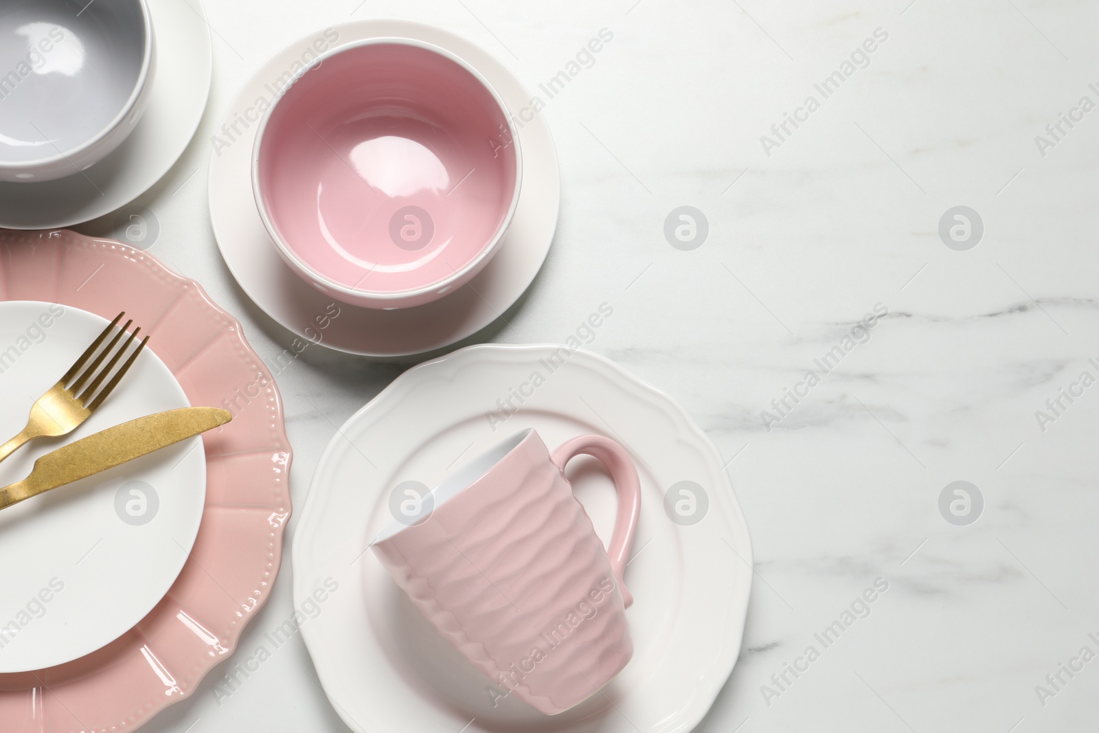 Photo of Beautiful ceramic dishware, cutlery and cup on white marble table, flat lay. Space for text