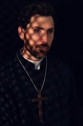 Catholic priest wearing cassock in confessional booth