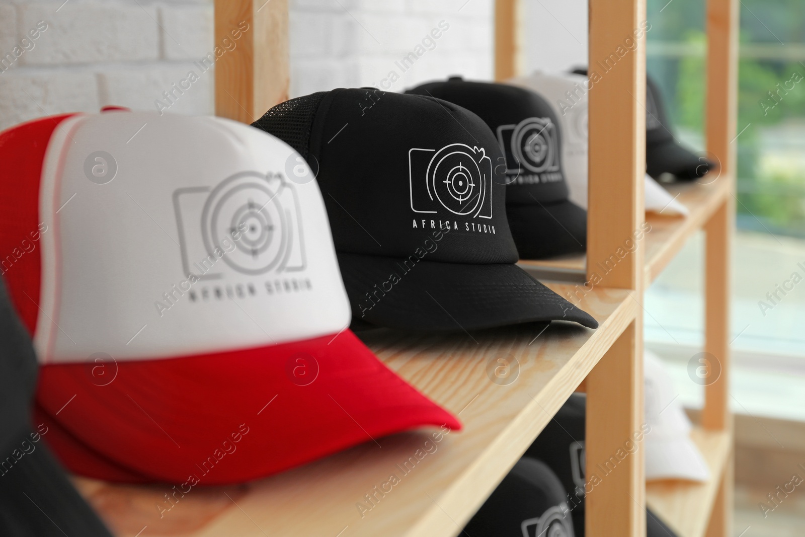 Photo of Different caps with logo on wooden shelf in shop