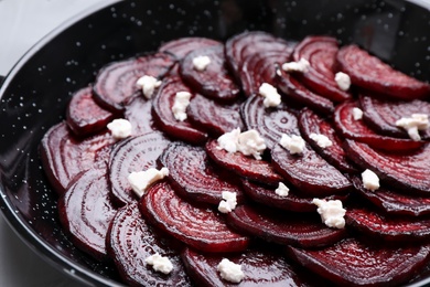 Photo of Roasted beetroot slices with feta cheese in wok pan, closeup