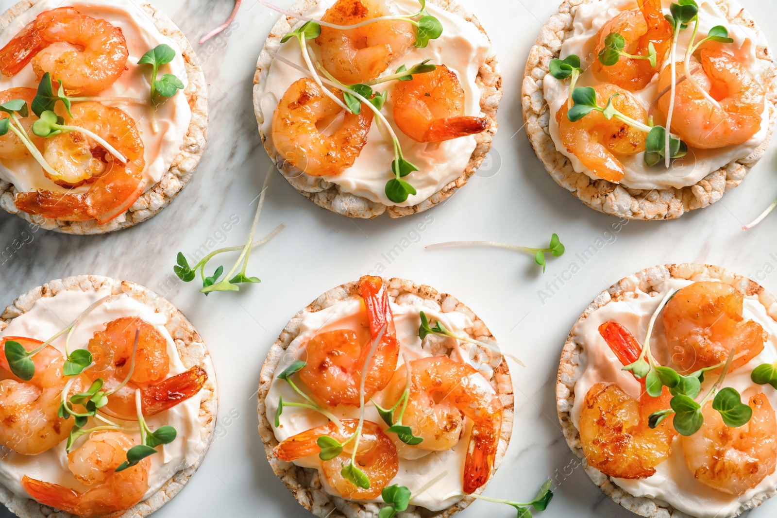 Photo of Delicious small sandwiches with shrimps on marble board