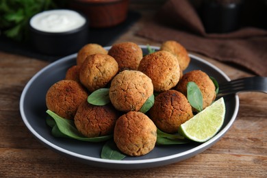 Photo of Delicious falafel balls with lime on wooden table, closeup