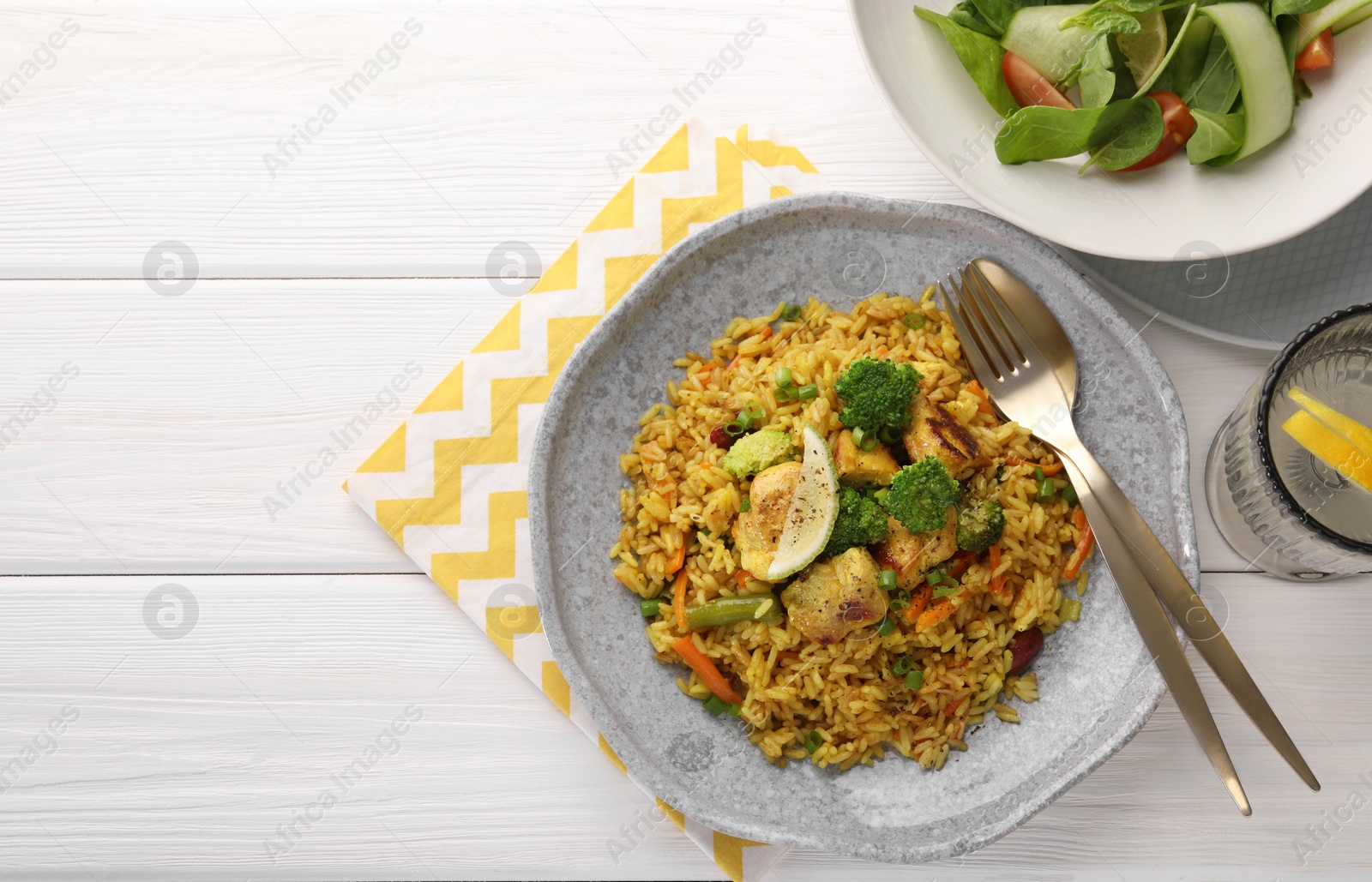 Photo of Tasty rice with meat and vegetables in plate served on white wooden table, flat lay. Space for text