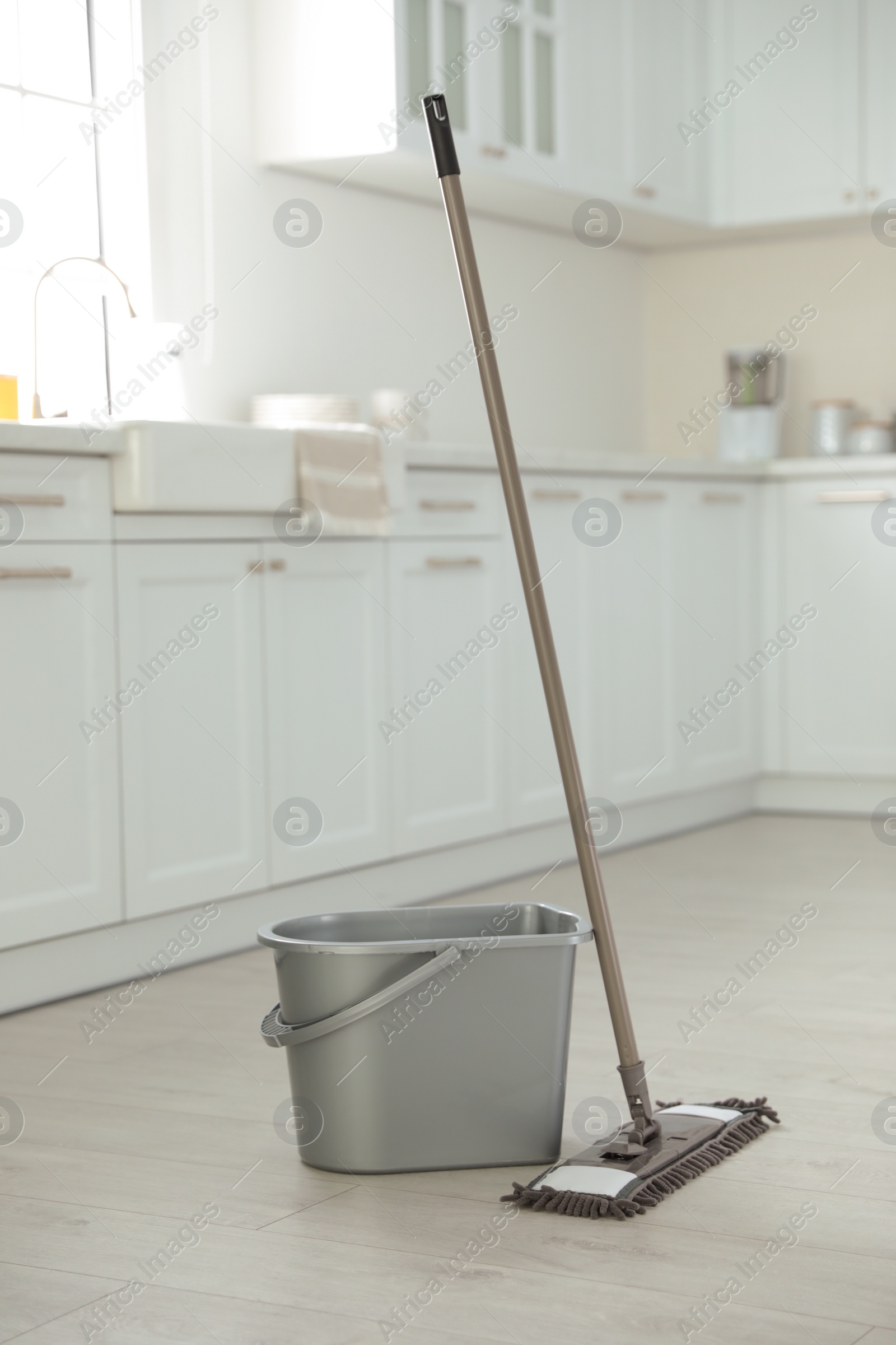 Photo of Mop and plastic bucket in kitchen. Cleaning supplies