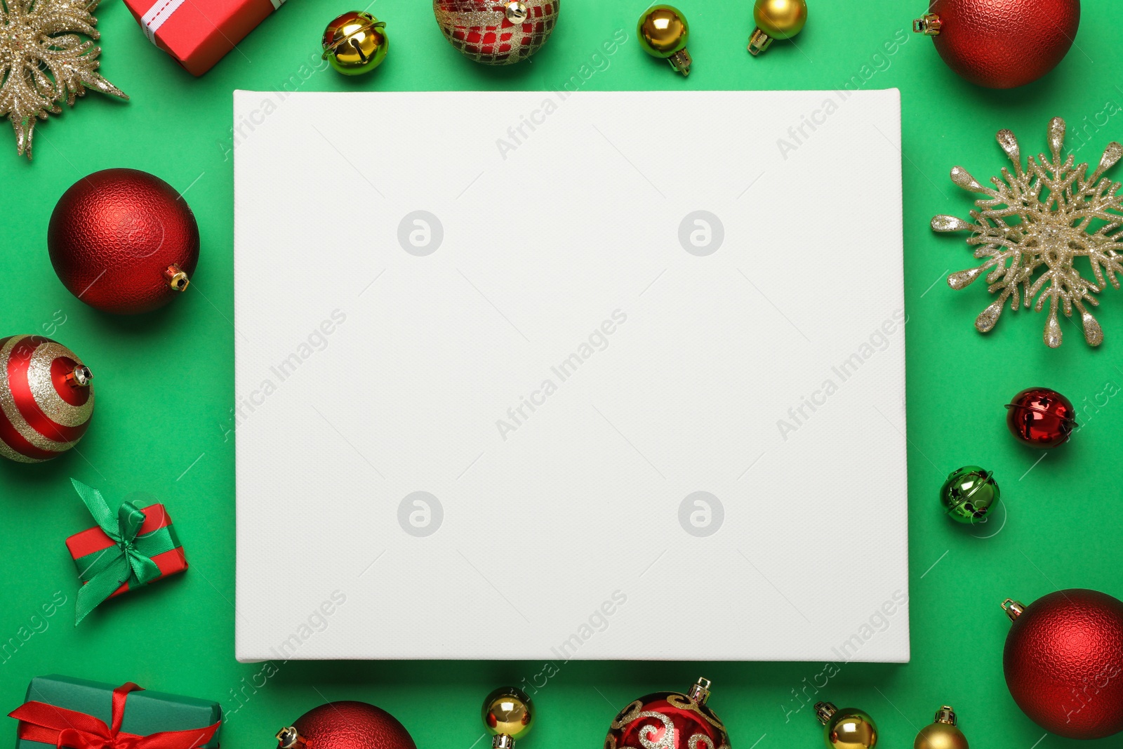 Photo of Flat lay composition with blank canvas and Christmas decor on green background. Mockup for design