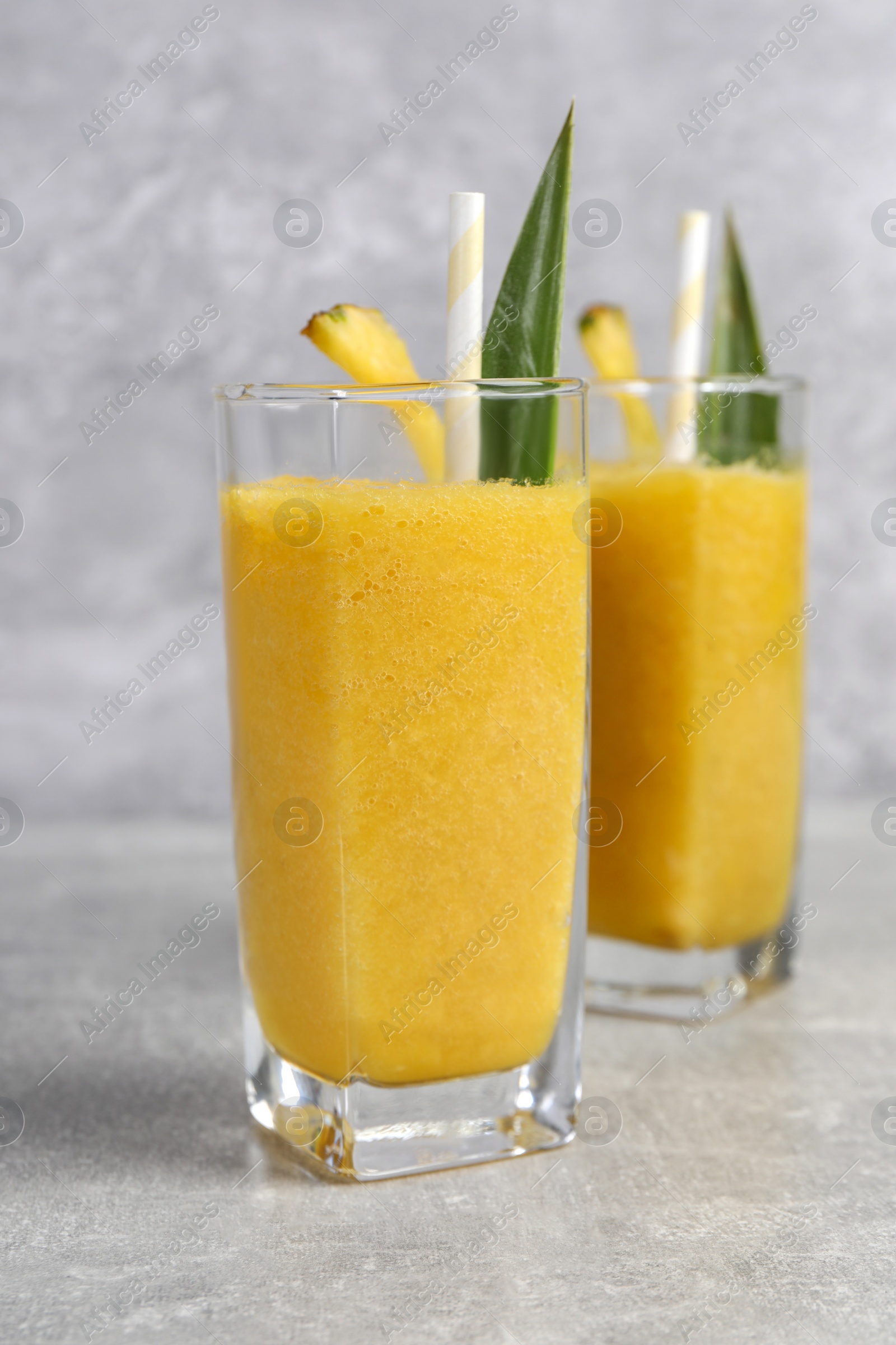 Photo of Tasty pineapple smoothie on light gray table