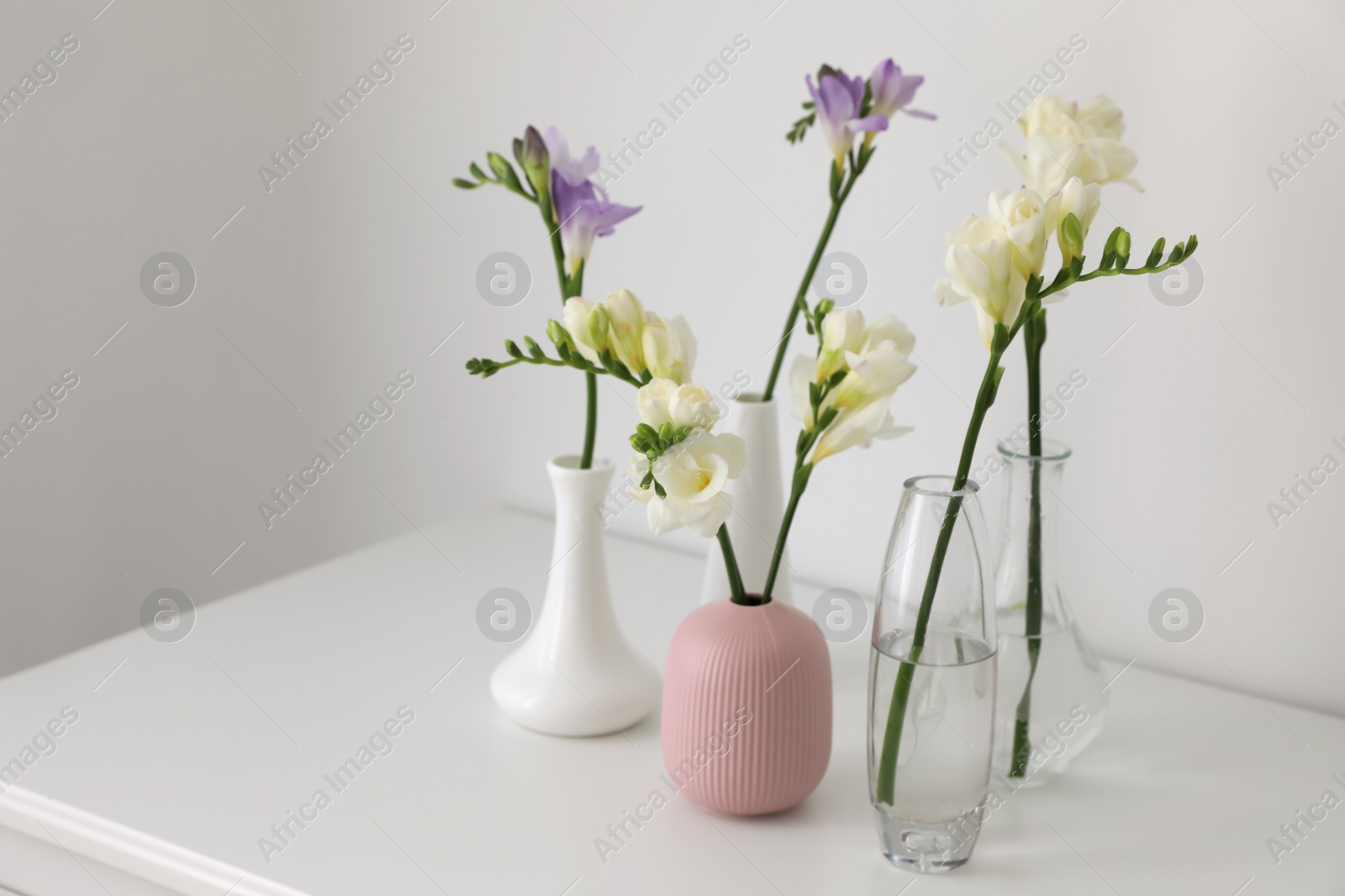 Photo of Beautiful spring freesia flowers on white table in room