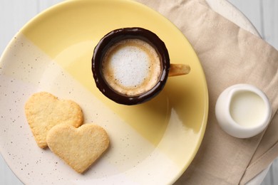 Photo of Delicious edible biscuit cup with coffee, milk and heart shaped cookies on table, flat lay