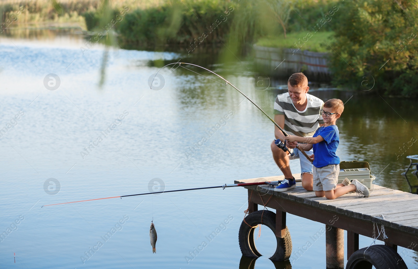 Photo of Dad and son fishing together on sunny day