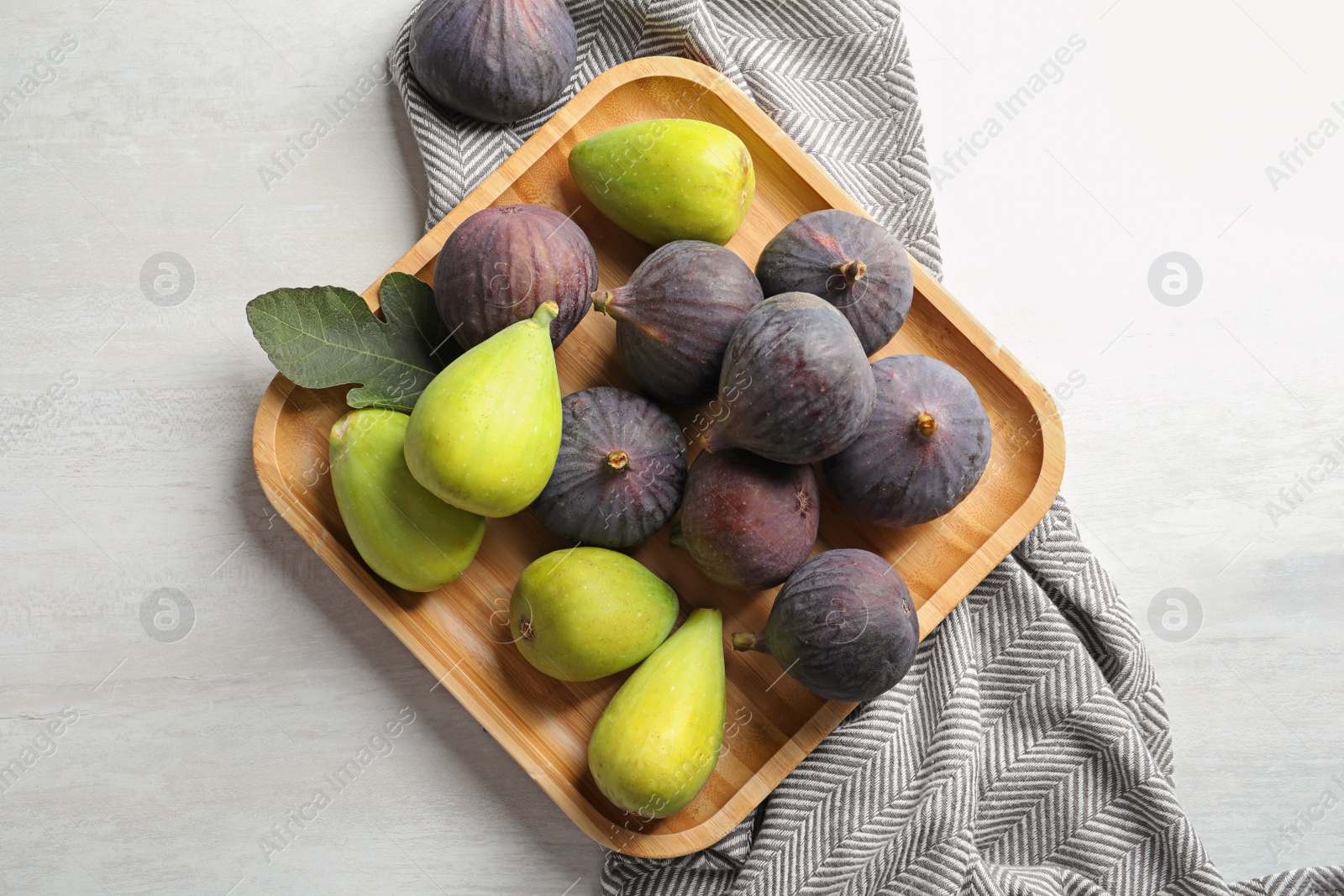 Photo of Plate with assorted ripe figs on light background, top view