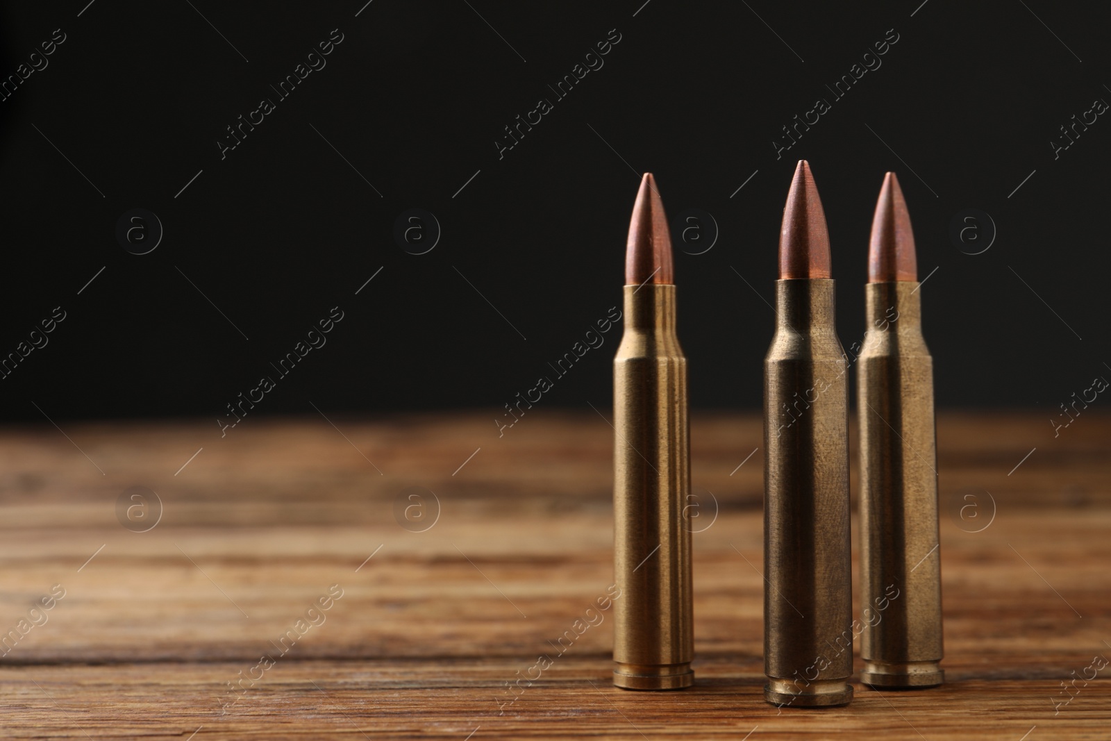 Photo of Three bullets on wooden table. Space for text