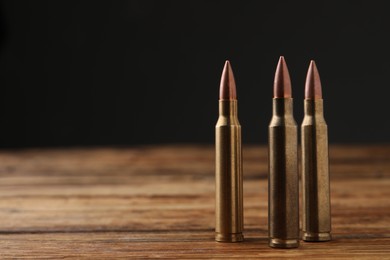 Photo of Three bullets on wooden table. Space for text