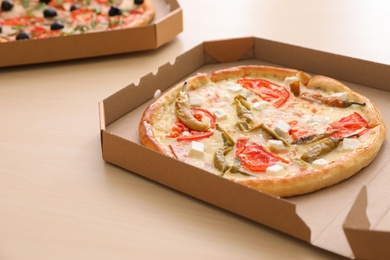 Cardboard boxes with tasty pizzas on wooden table