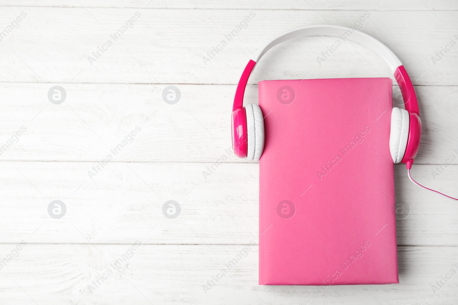 Photo of Book and headphones on white wooden background, flat lay. Space for text