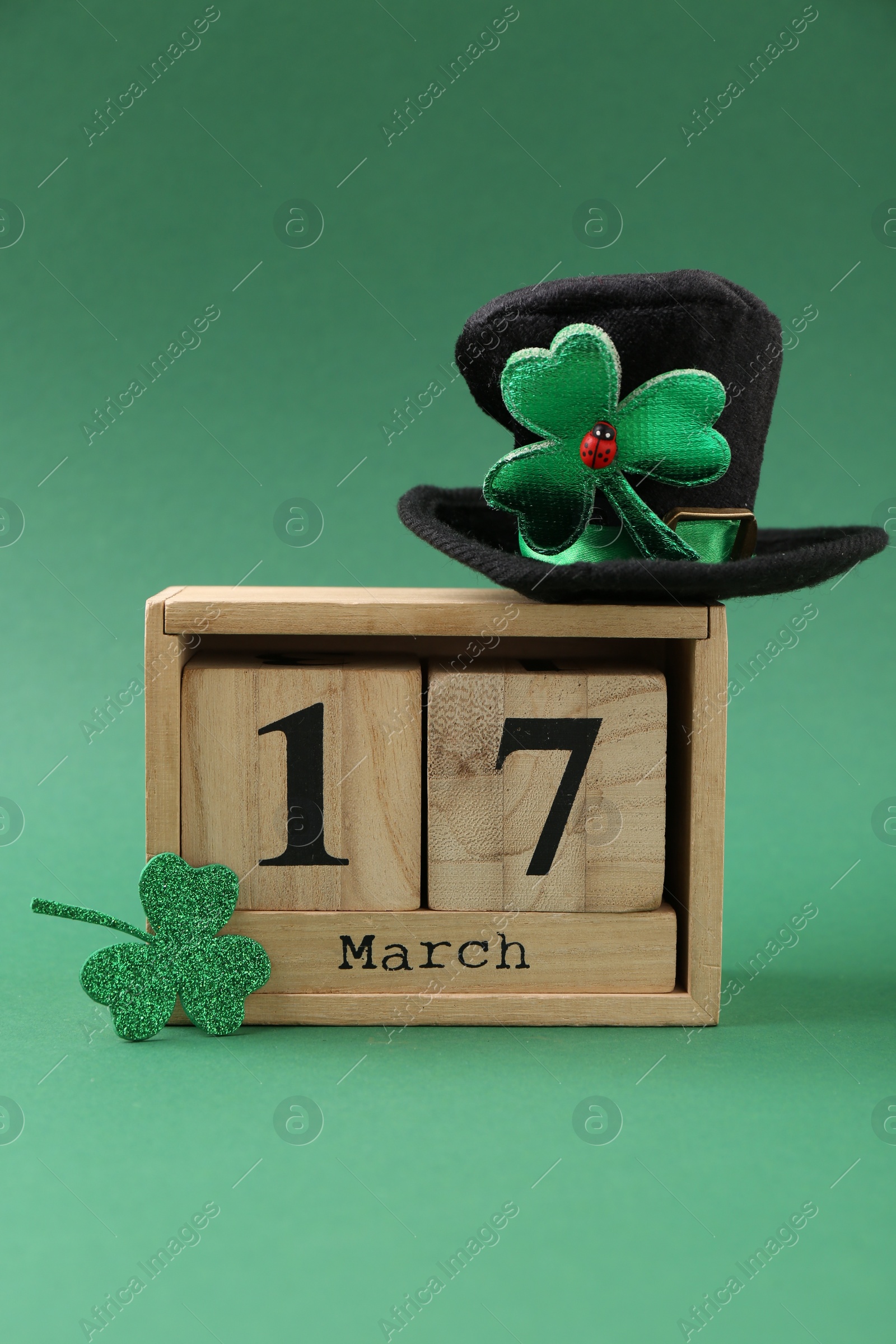 Photo of St. Patrick's day - 17th of March. Block calendar, leprechaun hat and decorative clover leaf on green background