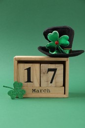 Photo of St. Patrick's day - 17th of March. Block calendar, leprechaun hat and decorative clover leaf on green background