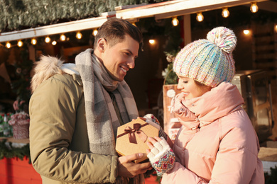 Photo of Happy couple with Christmas gift at winter fair