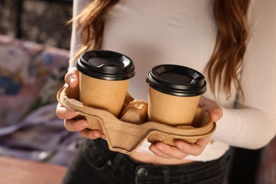 Woman holding paper coffee cups outdoors, closeup