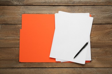 Orange file with blank sheets of paper and pen on wooden table, top view. Space for design