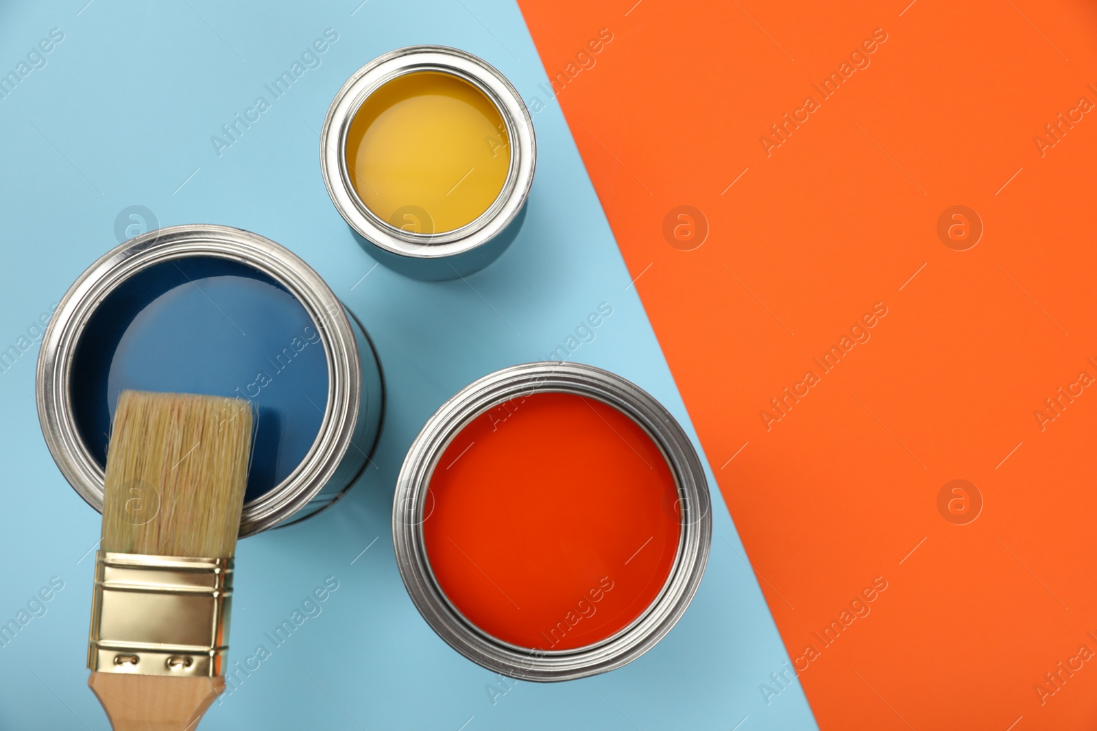 Photo of Cans of different paints and brush on color background, flat lay. Space for text