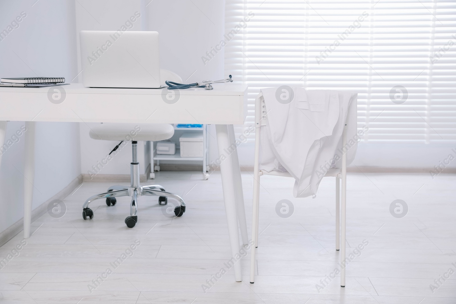 Photo of White doctor's gown hanging on chair in clinic