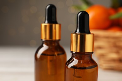 Photo of Bottle of tangerine essential oil on blurred background, closeup