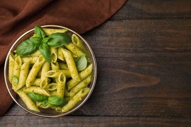 Photo of Delicious pasta with pesto sauce and basil on wooden table, top view. Space for text