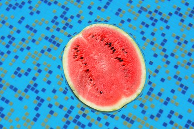 Photo of Half of fresh juicy watermelon in swimming pool, top view