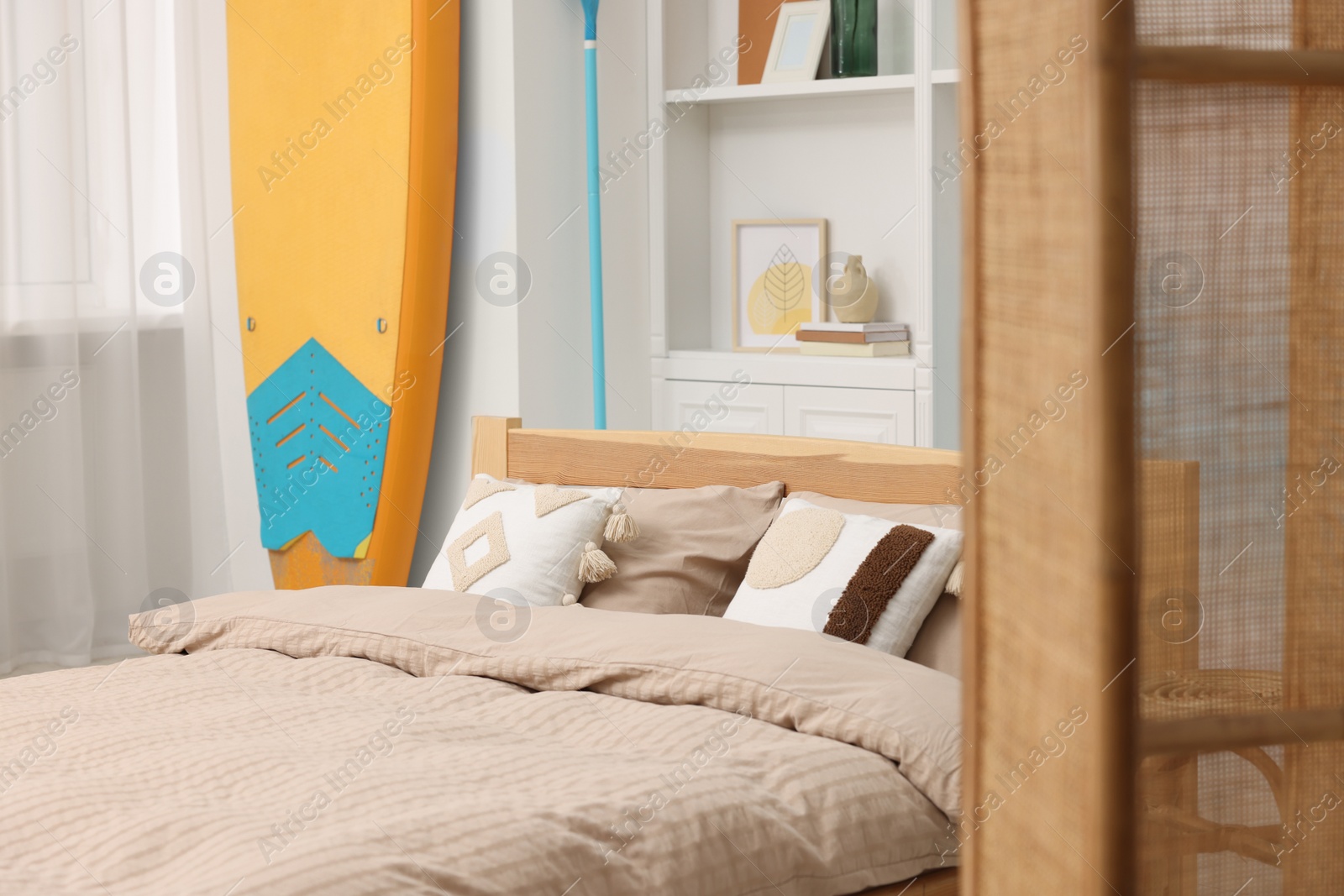 Photo of SUP board, bed and furniture in room. Interior design