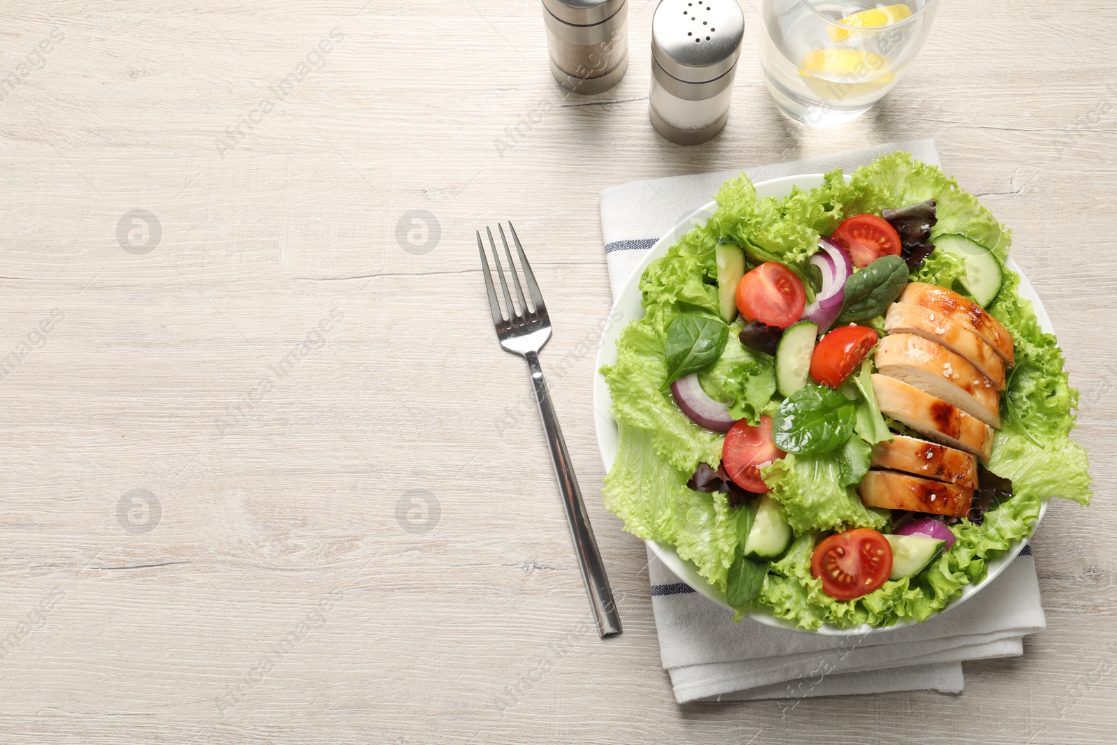 Photo of Delicious salad with chicken and vegetables served on wooden table, top view. Space for text