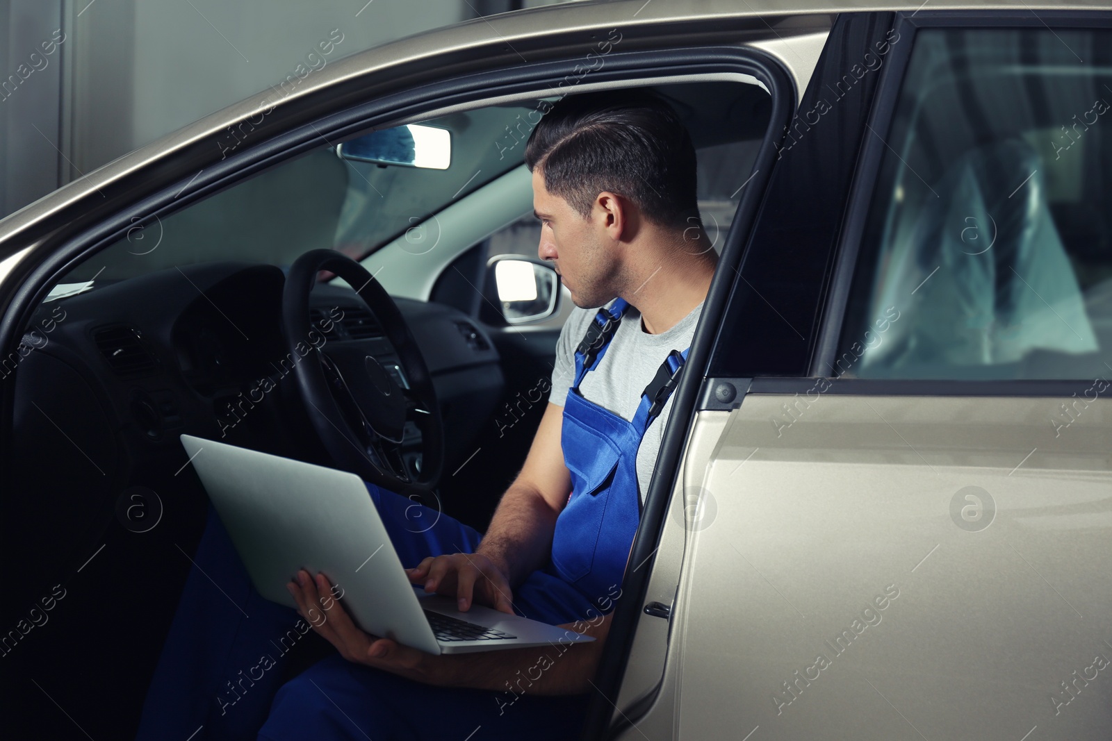 Photo of Mechanic with laptop doing car diagnostic at automobile repair shop