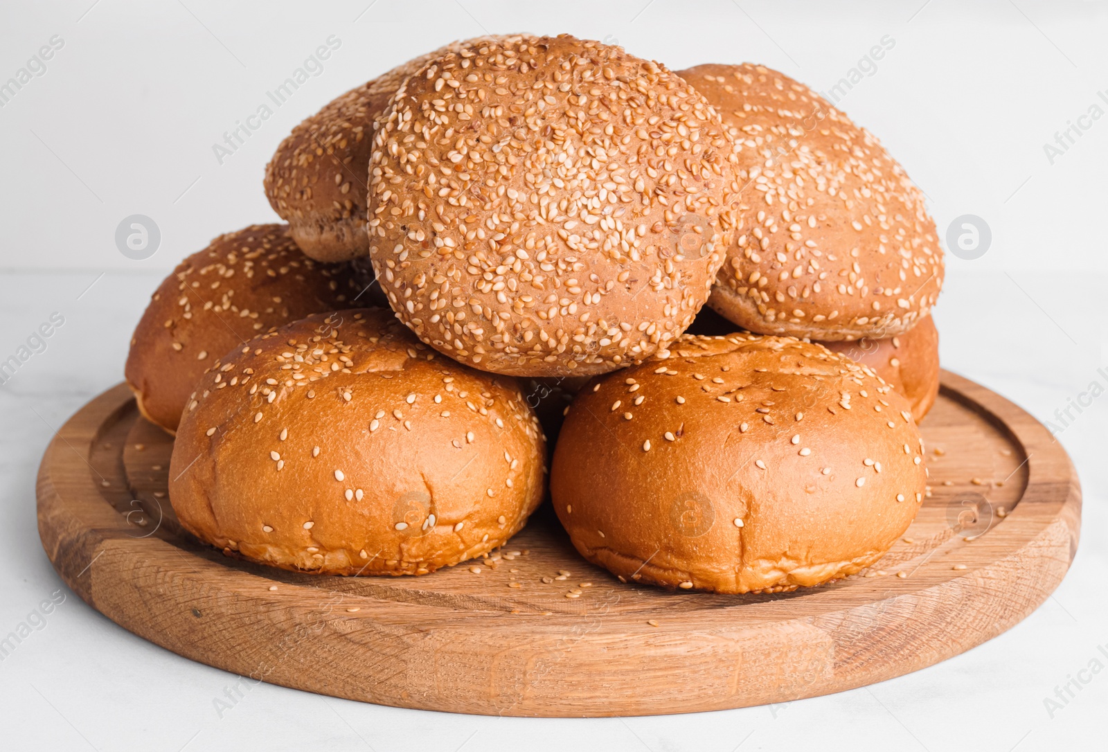 Photo of Fresh buns with sesame seeds on white marble table