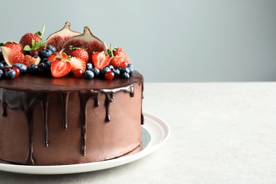 Fresh delicious homemade chocolate cake with berries on table against color background. Space for text