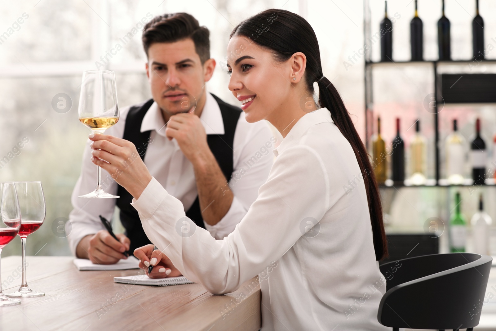 Photo of Sommeliers tasting different sorts of wine at table indoors