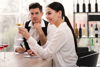 Sommeliers tasting different sorts of wine at table indoors